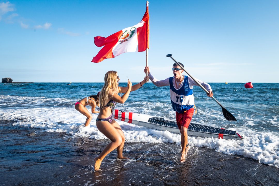 Itzel Delgado is handed his homeland flag for Peru upon his win at the ISA World Championships.